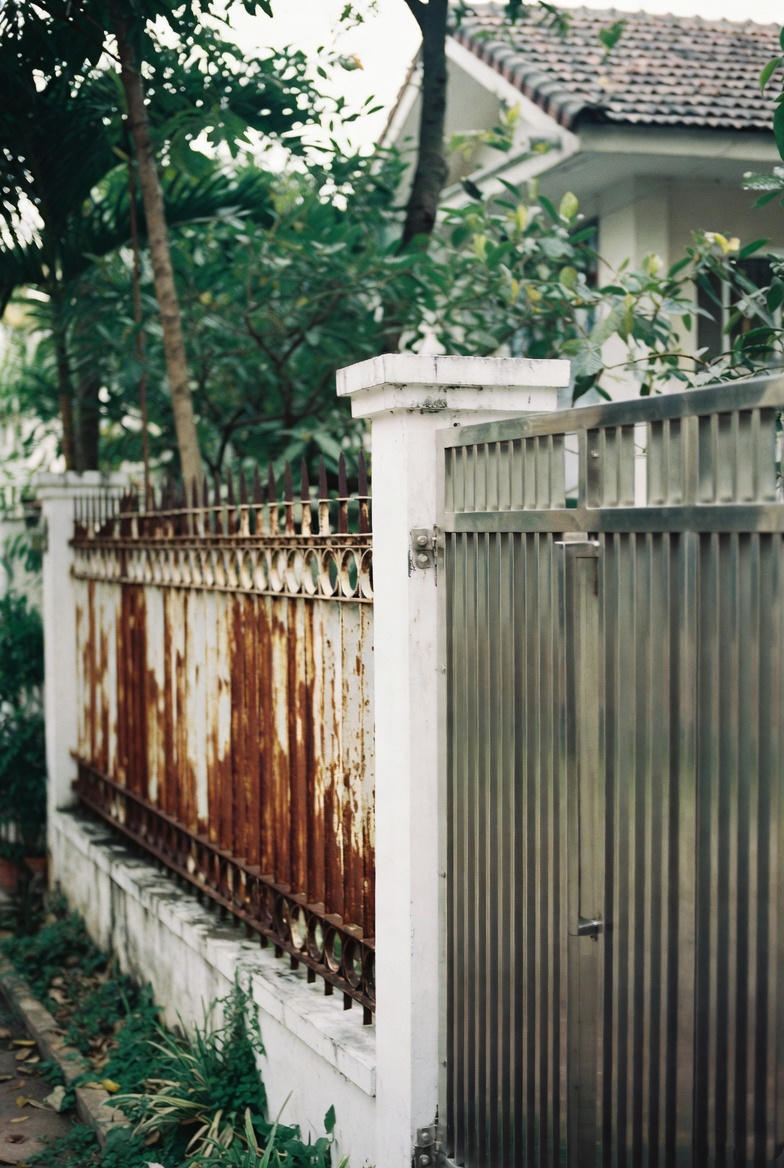 So sánh trực quan hàng rào sắt bị gỉ sét và hàng rào inox mới sáng bóng tại nhà phố